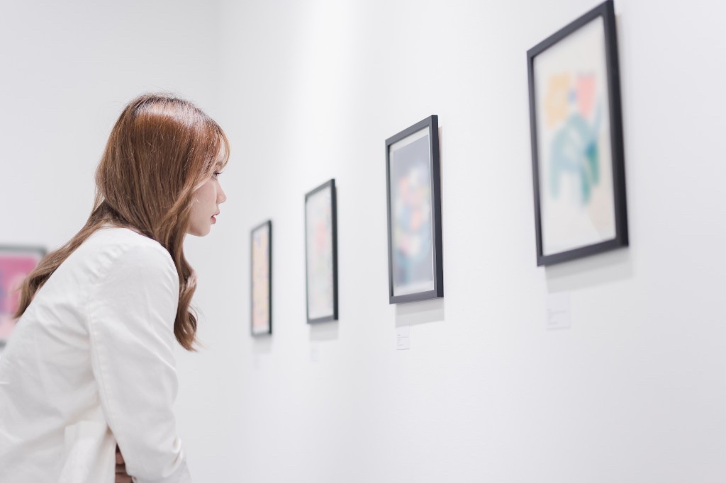 A young woman studying artwork in a gallery
